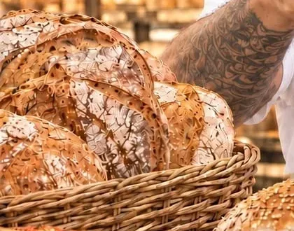 Cesto di pane di Panificio Falco sul bancone, con le pagnotte in vetrina sullo sfondo